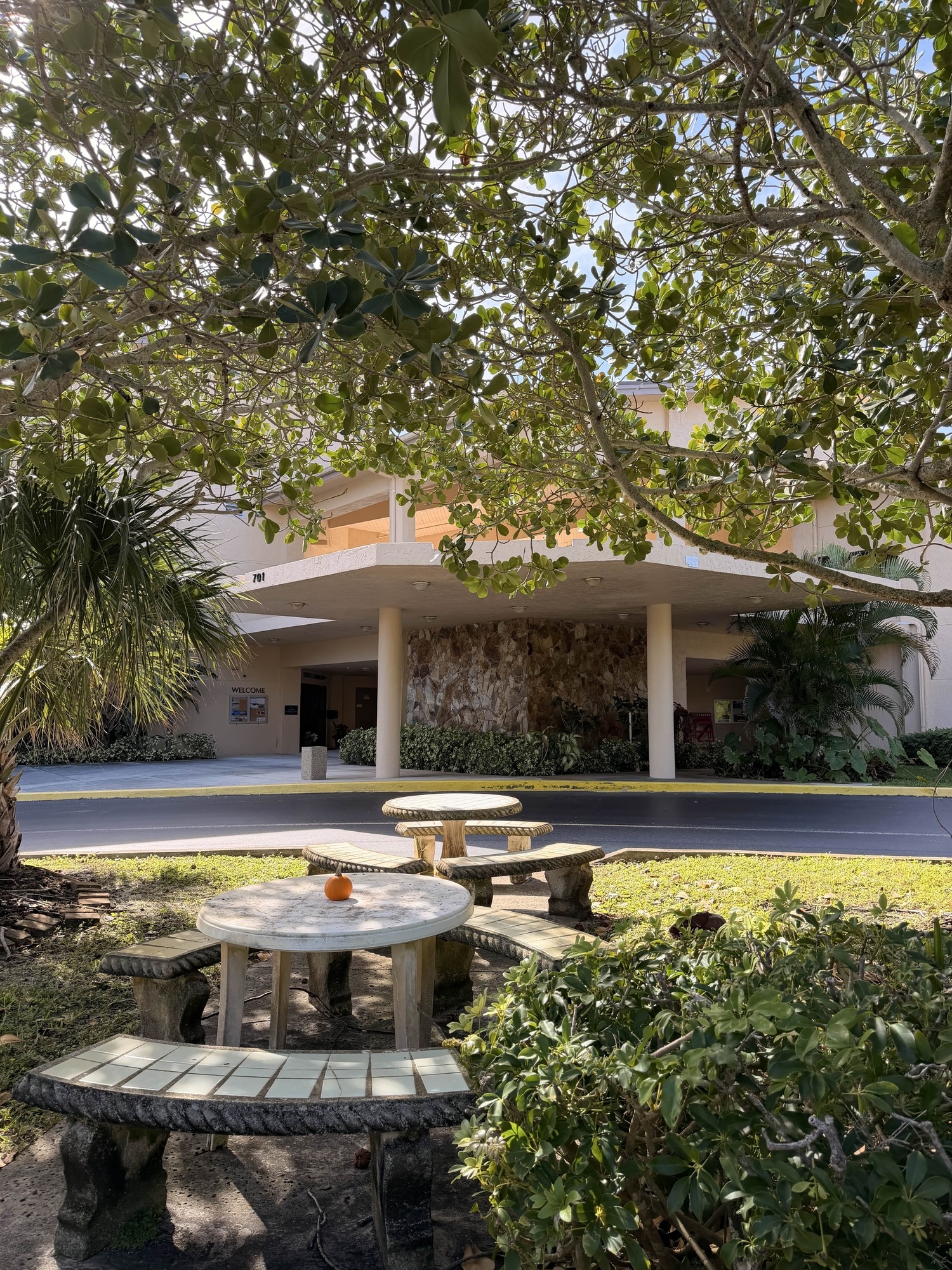 The entrance courtyard at 701 Ocean Drive: stone tables and benches shaded by sea grape trees