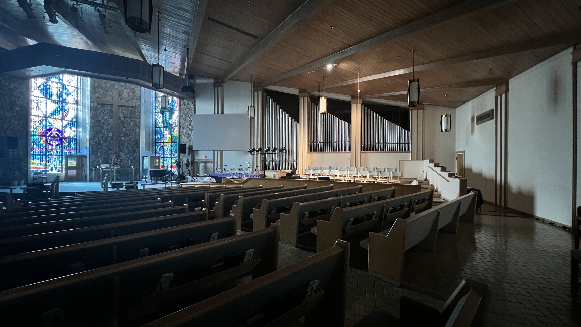 The Oceanview Church sanctuary: wood ceiling, stained glass windows, organ pipes, and rows of pews